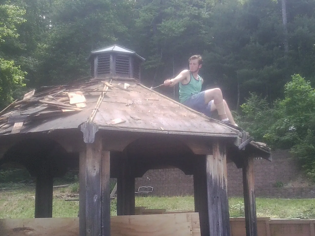 Tearing the old roof off a wooden gazebo before new shakes in Millersville