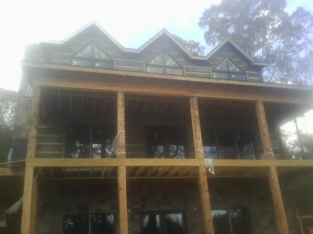 Dormers and porch framing on a large log home under construction — Roof Coating work by our crew in Millersville
