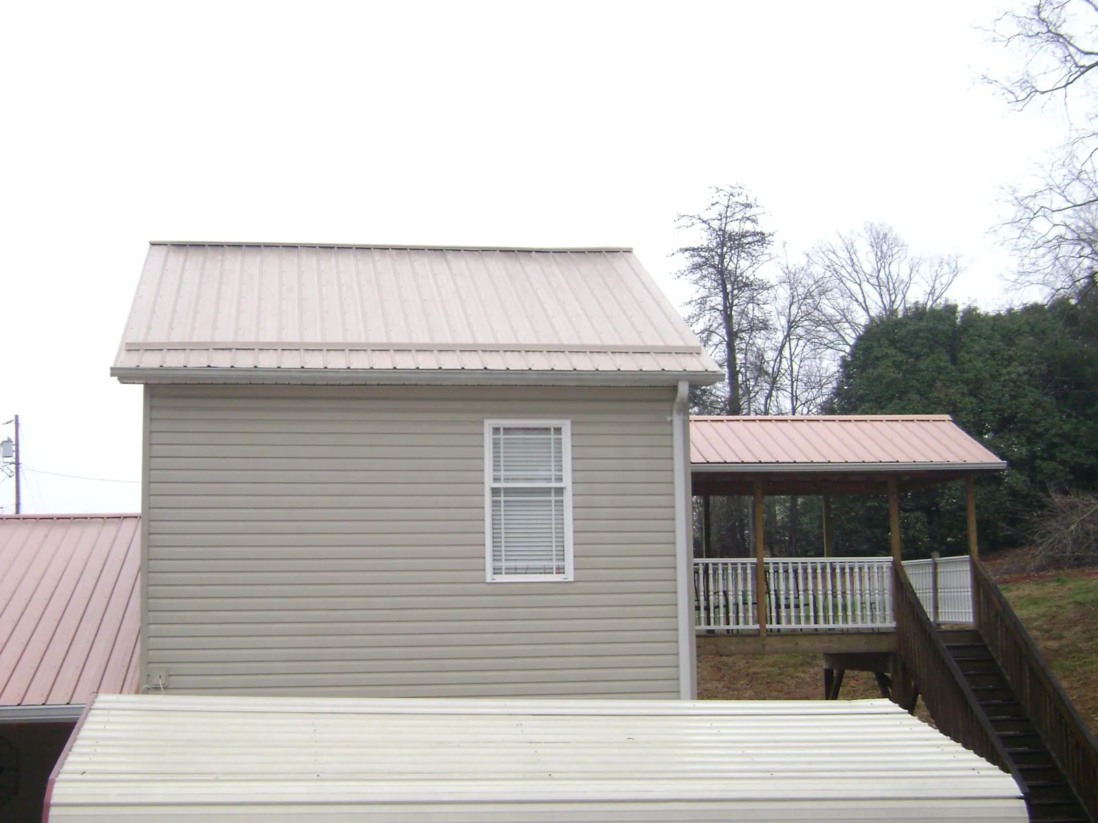 Tan metal roofs on a two story addition and attached porch, from a Roof Replacement job in Millersville