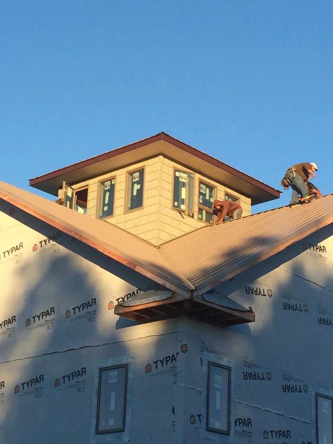 Roofers working around a rooftop cupola on a new metal roof at sunset — Roof Waterproofing in Millersville by Roofing Brothers